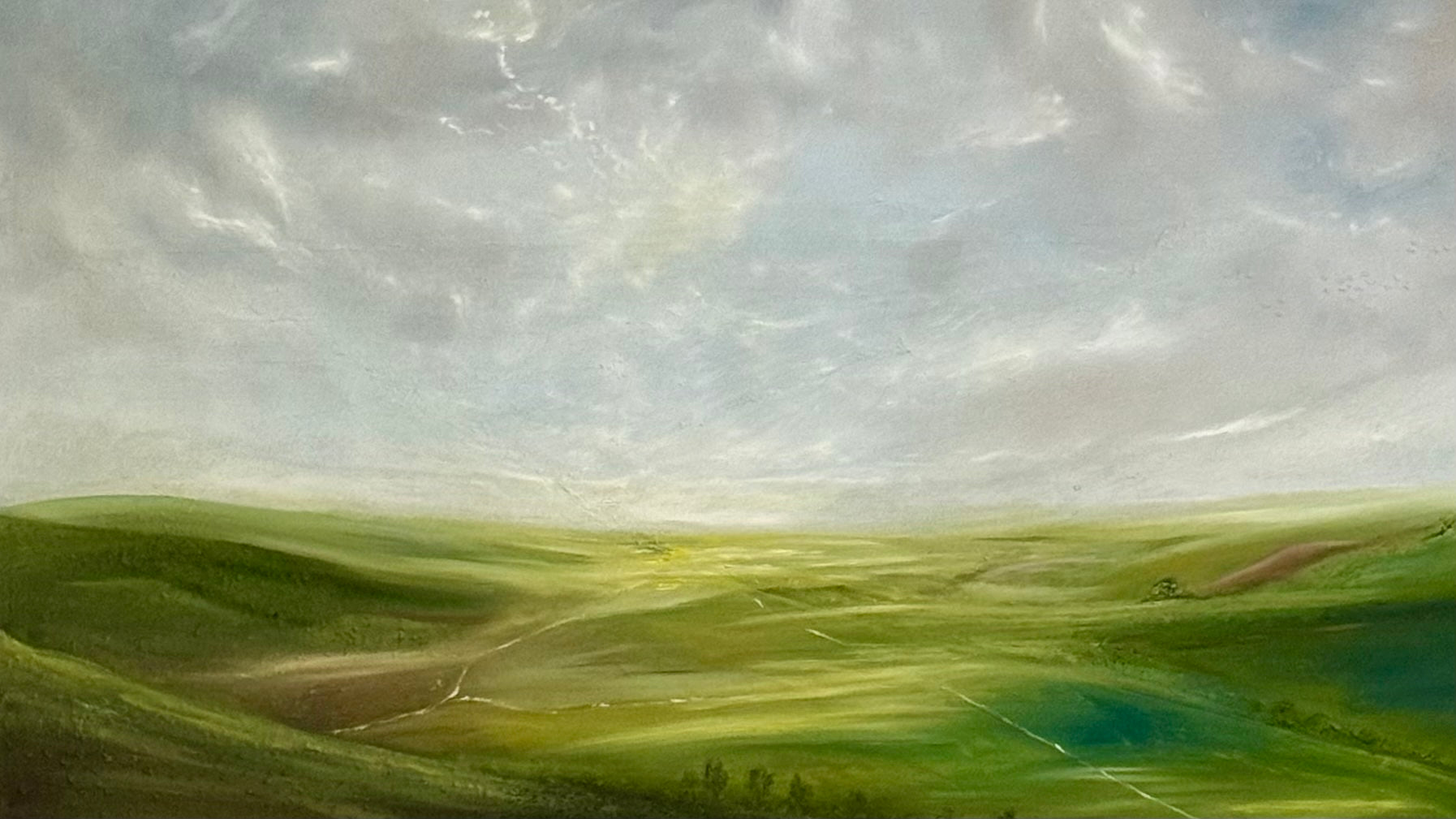 Green landscape with rolling hills and a cloudy sky