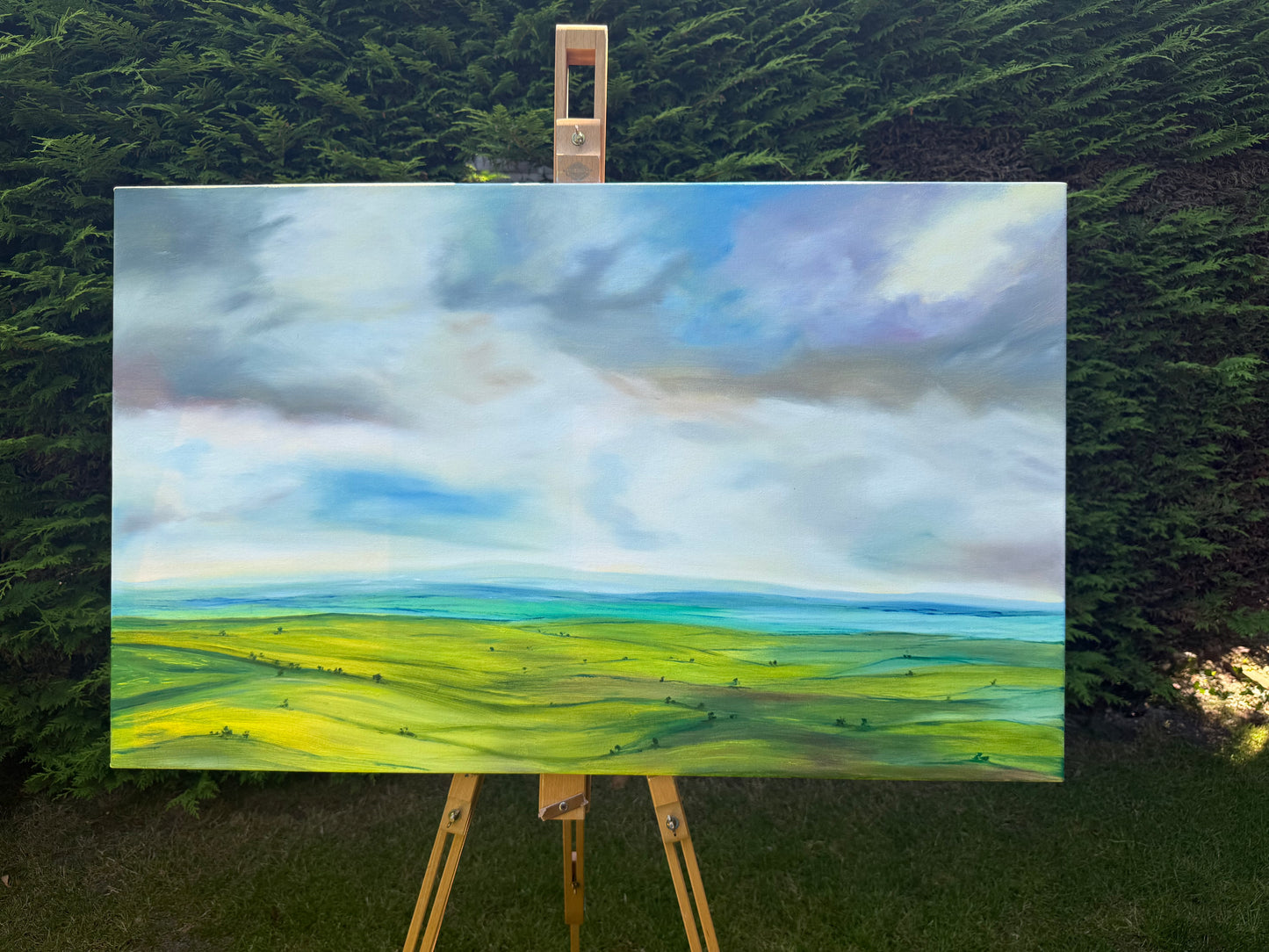 Peace original oil landscape painting of rolling green fields under a moody, dramatic grey and purple storm sky by Caroline Manson