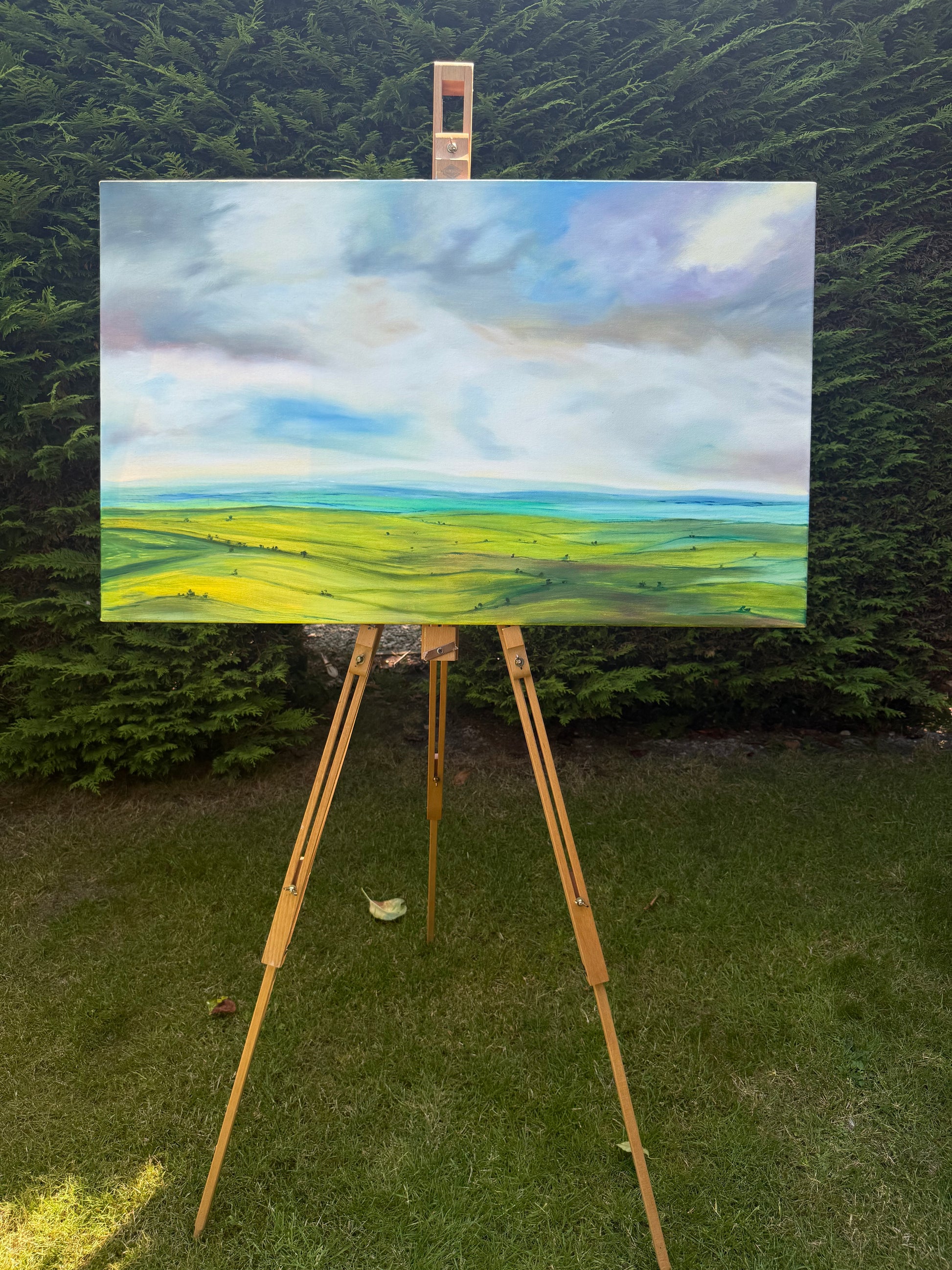 Peace original oil landscape painting of rolling green fields under a moody, dramatic grey and purple storm sky by Caroline Manson