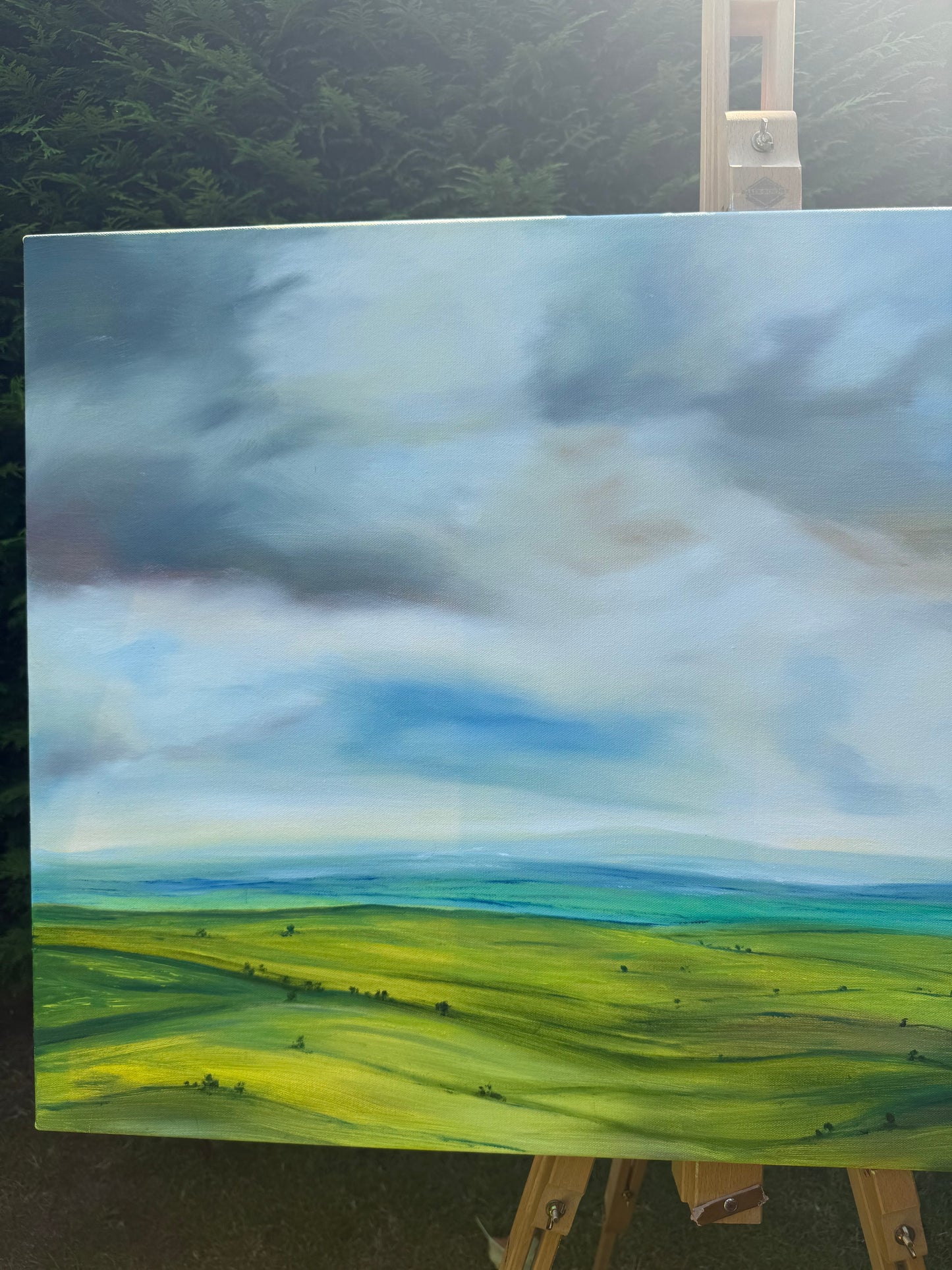 Peace original oil landscape painting of rolling green fields under a moody, dramatic grey and purple storm sky by Caroline Manson