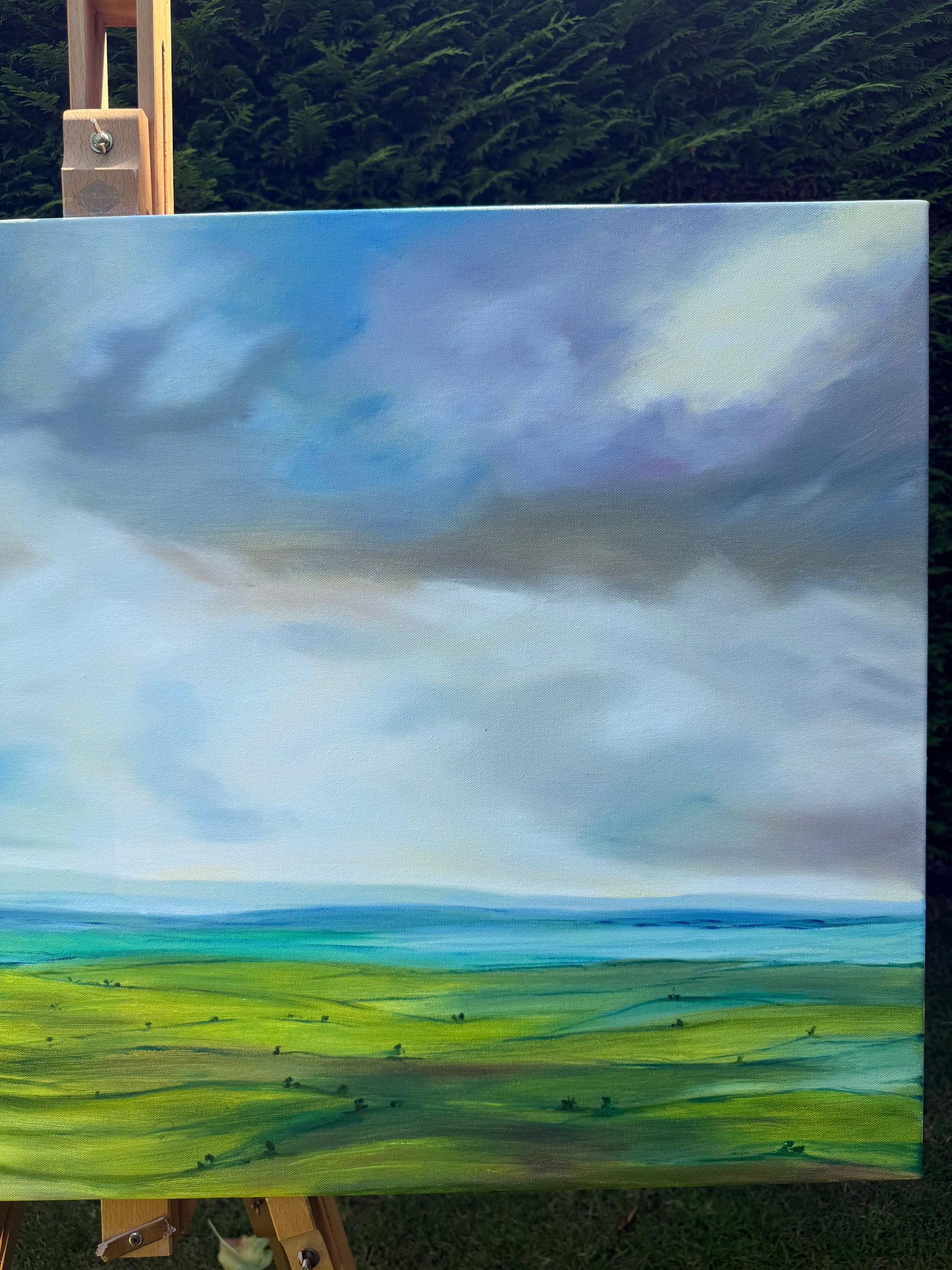 Peace original oil landscape painting of rolling green fields under a moody, dramatic grey and purple storm sky by Caroline Manson